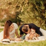 A happy family having a picnic in a lush green park setting during the day.